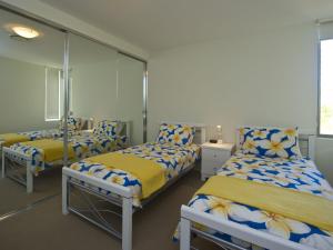 a room with three beds with blue and yellow sheets at Blue on Blue Apartment 921 in Nelly Bay +9 photos
