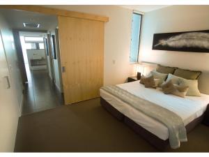 a bedroom with a large bed and a sliding door at 1 Bright Point Apartment 5201 in Nelly Bay