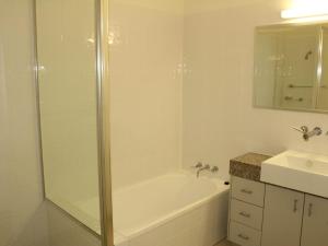 a bathroom with a shower and a tub and a sink at Beachside Apartment 17 in Nelly Bay