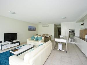 sala de estar con 2 sofás blancos y cocina en Blue on Blue Apartment 812, en Nelly Bay