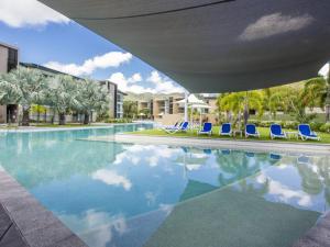 a swimming pool with blue chairs and palm trees at Blue on Blue Penthouse Apartment 335 in Nelly Bay