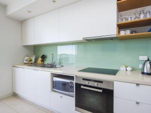 a white kitchen with a sink and a microwave at 1 Bright Point Apartment 5102 in Nelly Bay