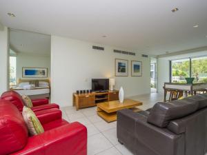 a living room with two red couches and a television at Blue on Blue Apartment 1011 in Nelly Bay