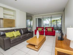 a living room with a leather couch and red chairs at Blue on Blue Apartment 1011 in Nelly Bay