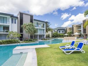 a swimming pool with lounge chairs next to a building at Blue on Blue Apartment 1011 in Nelly Bay