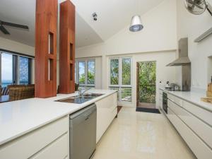 a large kitchen with white counters and windows at Driftwood in Picnic Bay