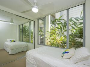 a bedroom with a bed and a large window at Blue on Blue Apartment 912 in Nelly Bay +16 photos