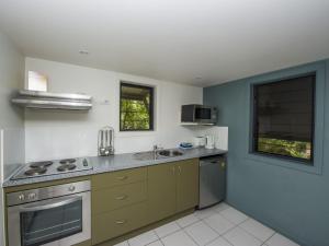 uma cozinha com um lavatório e um fogão forno superior em Canopy Chalet 10 em Nelly Bay
