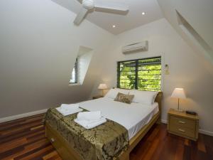a bedroom with a large white bed and a window at Canopy Chalet 10 in Nelly Bay