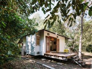 a tiny house in the woods with a porch at The Little Bush Hut in Nelly Bay