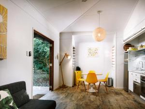 a kitchen and dining room with a table and yellow chairs at The Little Bush Hut in Nelly Bay