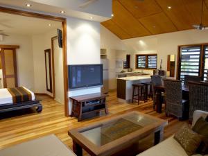 Una sala de estar con un televisor grande y una cocina. en Pure Magnetic Villa 3, en Nelly Bay