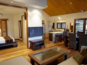 a living room with a large television and a kitchen at Pure Magnetic Villa 7 in Nelly Bay