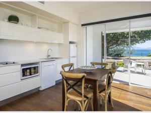a kitchen with a table and chairs and a view of the ocean at Reflections Emerald Villa 1 in Picnic Bay