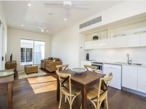 a kitchen and living room with a wooden table and chairs at Reflections Emerald Villa 1 in Picnic Bay