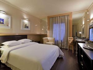 聖保羅的住宿－鉑爾曼聖保羅伊比拉普埃拉酒店，酒店客房设有一张大床和一张书桌。