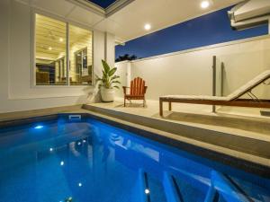Picnic Bay的住宿－Reflections Turquoise Villa 4，房屋设有1个带长凳和椅子的游泳池