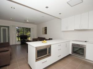 a kitchen with white cabinets and a living room at Woodville Beach Townhouse 6 in Arcadia