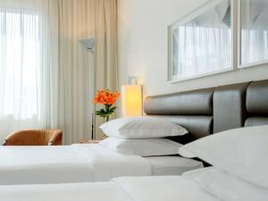 a hotel room with two beds and a vase with a flower at Grand Mercure Sao Paulo Vila Olimpia in Sao Paulo