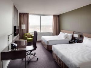 a hotel room with two beds and a desk and a chair at Pullman Adelaide in Adelaide