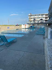a swimming pool with blue chairs and a building at Yankee Clipper Resort Motel in Wildwood Crest