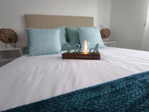 Una cama con almohadas azules y una vela. en Beachfront Apartment Nazaré en Nazaré
