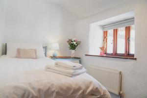 Un dormitorio blanco con una cama con toallas. en 'The Cottage' en Okehampton