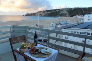 una mesa con un plato de comida y vino en el balcón en Beachfront Apartment Nazaré en Nazaré