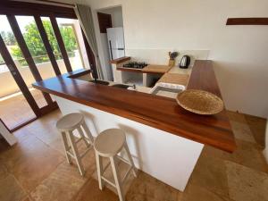 a kitchen with a counter with two stools and a counter top at Navegantes Nascente - Os Navegantes in Guajiru +20 photos