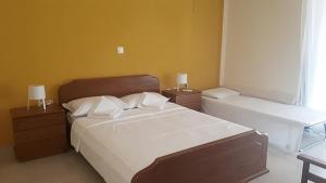 Alianthos Beach Apartment في فاري: غرفة نوم بسرير كبير وموقف ليلتين