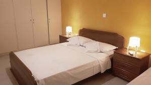 Alianthos Beach Apartment في فاري: غرفة نوم بسرير كبير مع مواقف ليلتين
