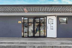 un edificio con puertas de cristal y una señal en él en Xingshe Alley Courtyard Hotel Beijing Wangfujing Forbidden City Branch, en Beijing