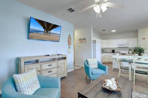 a living room with blue chairs and a table and a kitchen at Crawfishin for a Compliment in Port Aransas