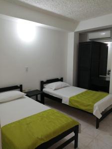 two beds in a hotel room with green sheets at Hotel Tame Real in Tame
