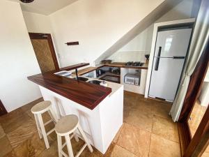 a kitchen with a counter with a sink and a refrigerator at Navegantes Poente - Os Navegantes in Guajiru