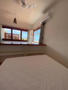 um quarto com uma cama branca e 2 janelas em Navegantes Poente em Guajiru