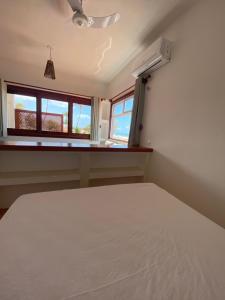 a bedroom with a white bed and two windows at Navegantes Poente - Os Navegantes in Guajiru