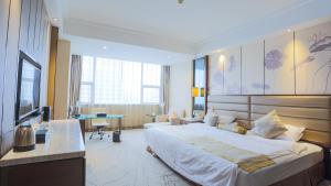 淮安にあるHuai'an Jinling Hotelの大きなベッドとデスクが備わるホテルルームです。
