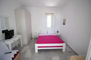 a white bedroom with a bed with a red blanket at Kiki's dream apartment balcony with sea views in Chrissi Akti