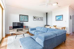 a living room with a blue couch and a tv at Canal Rocks Beachfront Apartments in Yallingup