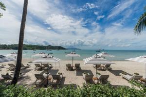 una playa con sillas y sombrillas y el océano en Melia Koh Samui, en Choeng Mon Beach