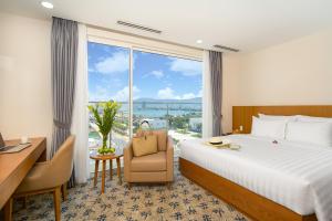 a hotel room with a bed and a desk and a window at Lamanga Hotel & Suites in Da Nang
