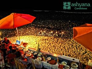 un grupo de personas sentadas alrededor de una mesa llena de comida en Ashyana Candidasa Beach Resort, en Candidasa