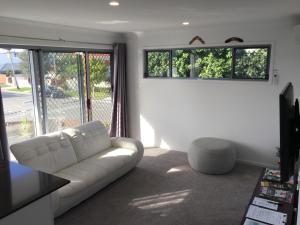 a living room with a white couch and a window at 2BD Family or Couple Guesthouse Upstairs near Turf club, HOTA in Bundall in Gold Coast