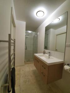 La salle de bains est pourvue d'un lavabo et d'un grand miroir. dans l'établissement Peaceful Mount Studio Moments to Beach & Downtown, à Mount Maunganui