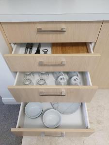 an open drawer of a cabinet with dishes in it at Peaceful Mount Studio Moments to Beach & Downtown in Mount Maunganui