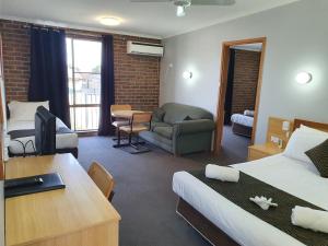 Habitación de hotel con cama, escritorio y sofá en Moonraker Motor Inn, en Parkes