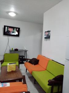 ein Wohnzimmer mit einem Sofa und einem TV in der Unterkunft Un T2 climatisé, une nuit in Kourou