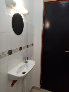ein Bad mit einem Waschbecken und einem Spiegel in der Unterkunft Un T2 climatisé, une nuit in Kourou