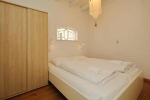 a bedroom with a bed with white sheets and a window at Holiday home het Zeepaardje in Noordwijkerhout